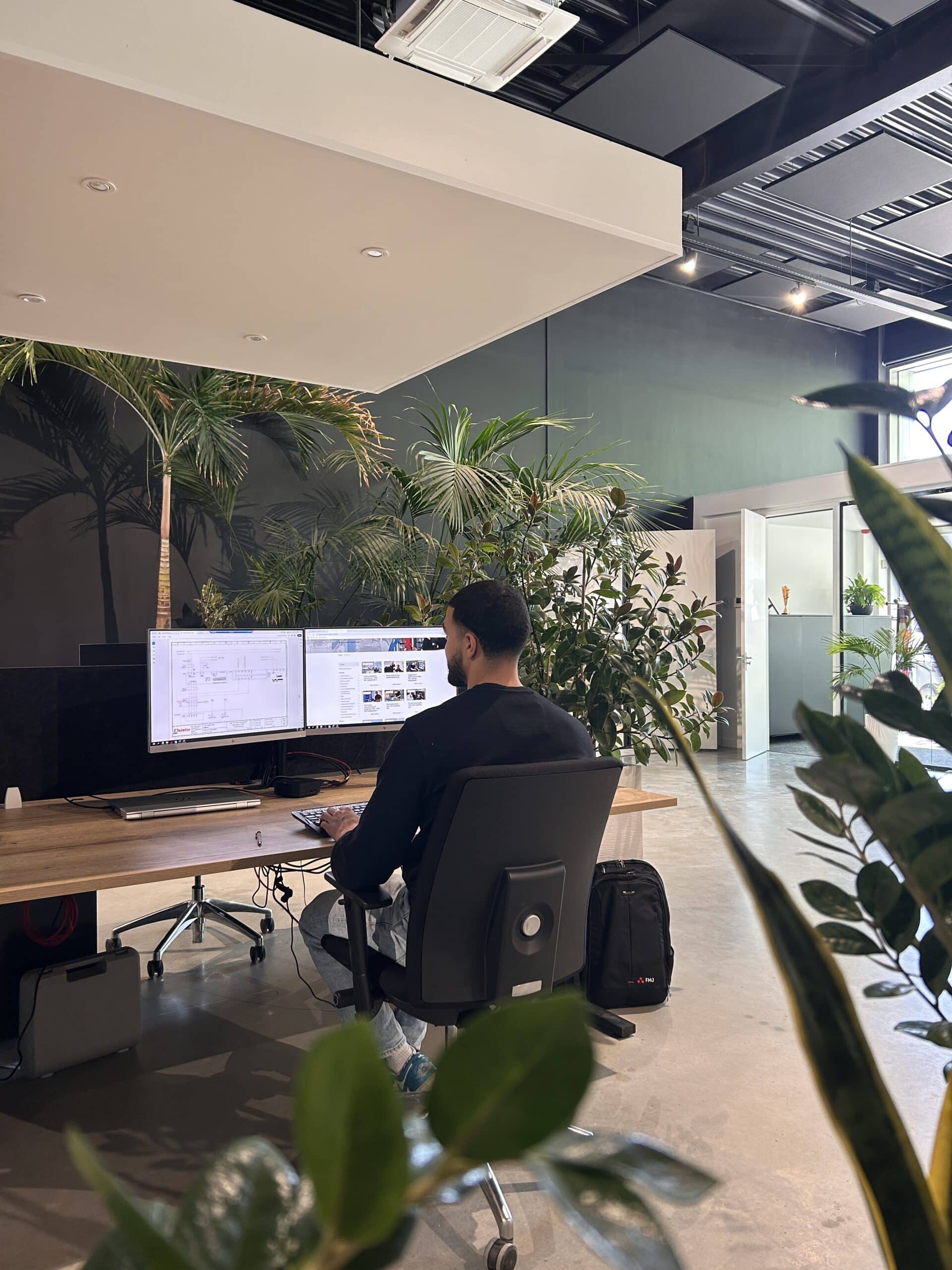 aankomend controller bij FMJ werkt achter computer in modern kantoor met groene plantenwand